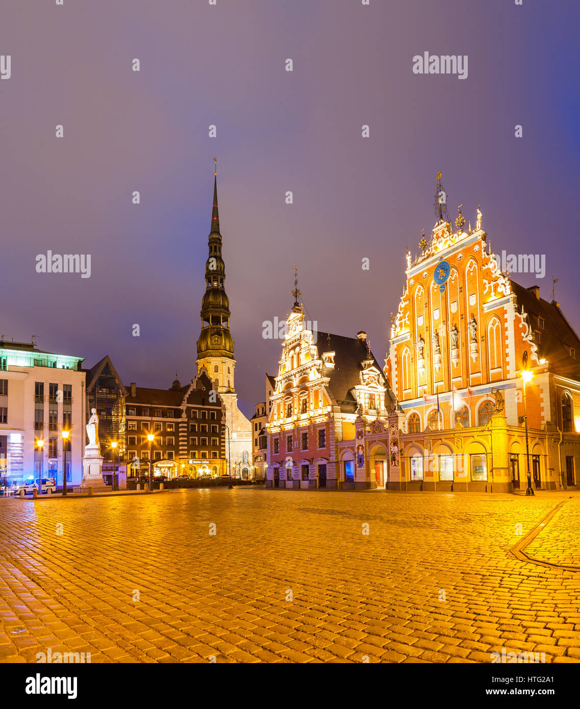 RIGA, Lettonie - 20 JUN 2016 : la Place de l'Hôtel de Ville avec Maison des Têtes Noires et église Saint Pierre dans la vieille ville de Riga dans la nuit. Banque D'Images