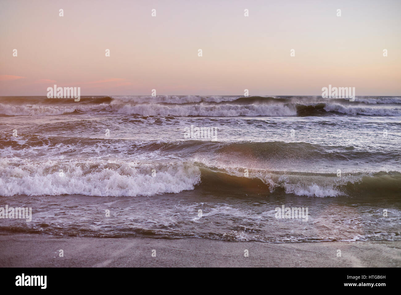 Les vagues de l'océan l'heure du coucher de soleil ciel rose clair avec panorama. Plage de l'océan avec des vagues Banque D'Images