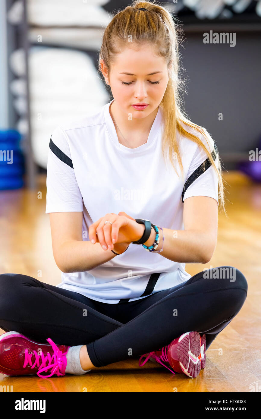 Femme à l'aide de Smart Watch While Sitting in Gym Banque D'Images