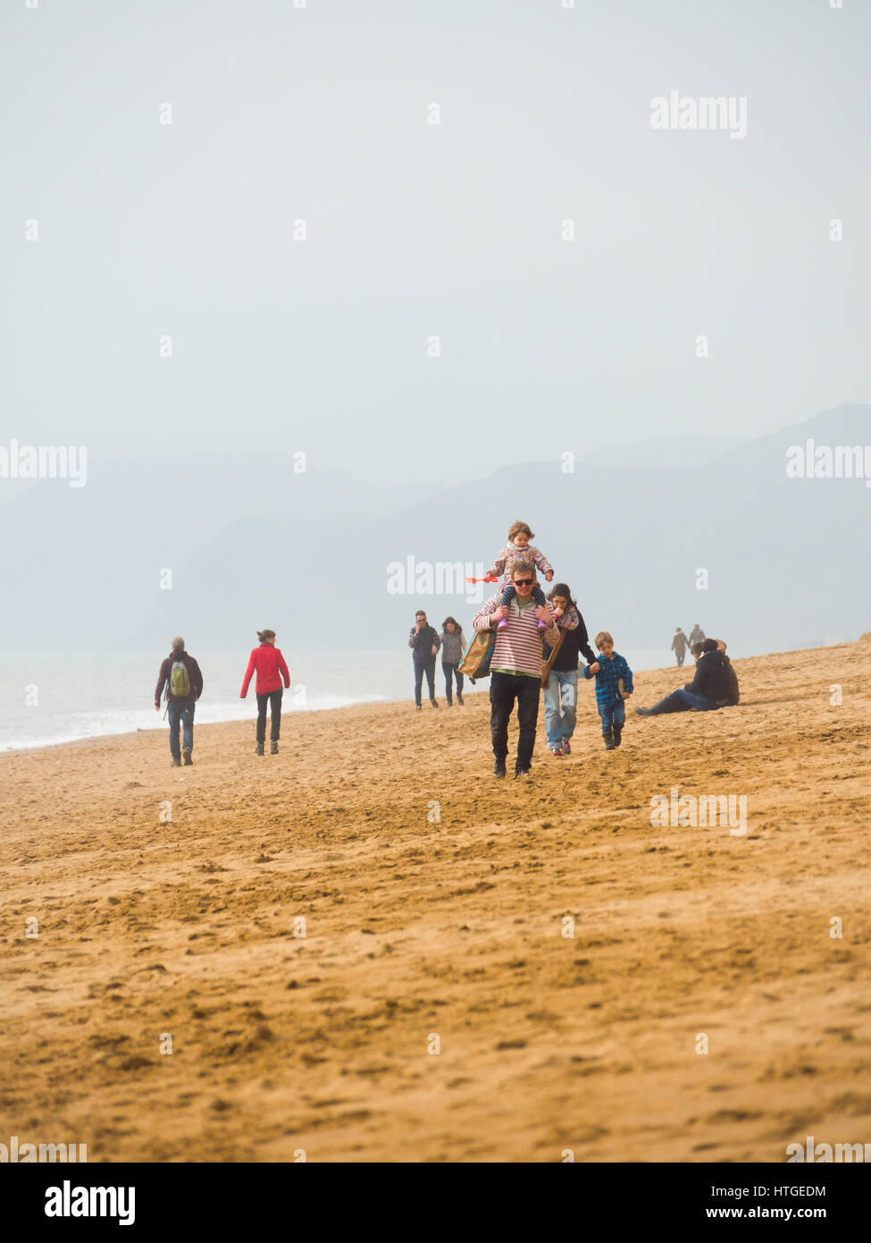 Burton Bradstock, Dorset, UK, le 11 mars 2017, les gens se promener le long de la plage Burton Bradstock plage un jour brumeux et voilé à West Dorset st Burton Bradstock beach, Dorset, UK. © Dan Tucker/Alamy Live News Banque D'Images