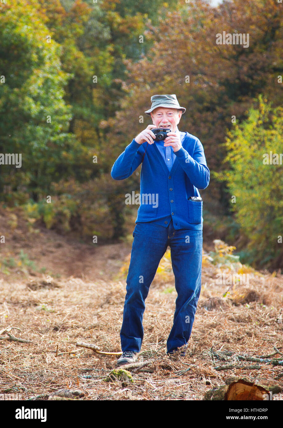 Un vieil homme de prendre une photo avec appareil photo compact ancien Banque D'Images