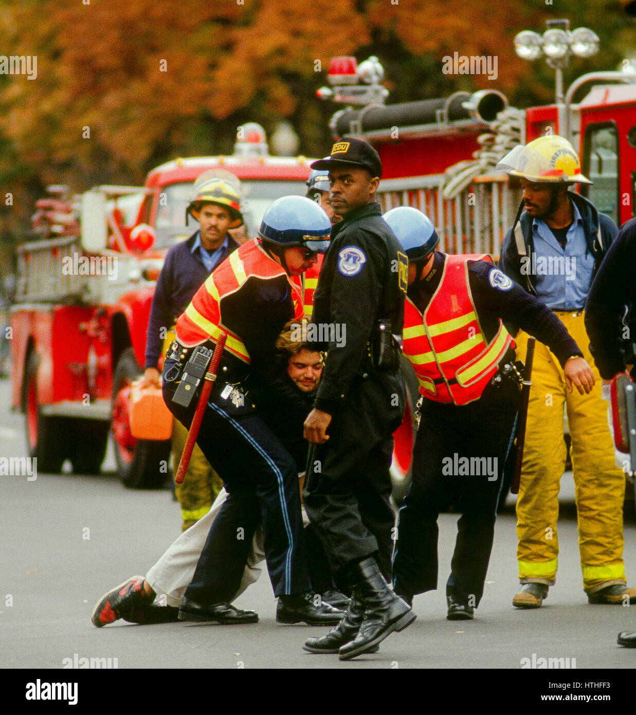 Capitole des officiers de police après l'arrestation et les menotter un sans-abri protestataire sur le front de l'Est du bâtiment de Capitol le traîner vers une ambulance pour être pris à un hôpital pour traitement comme DC pompiers et parmedics regardez sur Washington DC., octobre, 1988. Photo par Mark Reinstein Banque D'Images