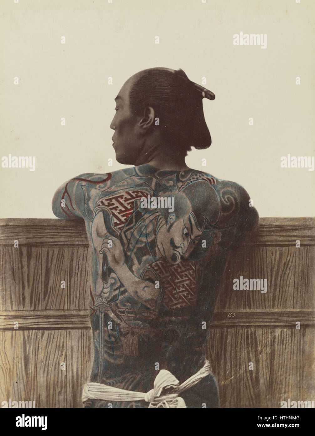 Cette photographie, probablement de Kimbei ou Stillfried, met en valeur un tatouage japonais traditionnel. L'image met en évidence des dessins complexes et des motifs symboliques associés à l'art japonais du tatouage, un artisanat riche en signification culturelle. Banque D'Images