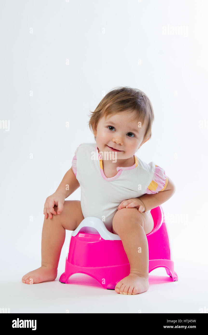 Little smiling girl sitting on un pot. Isolé sur fond blanc. Banque D'Images