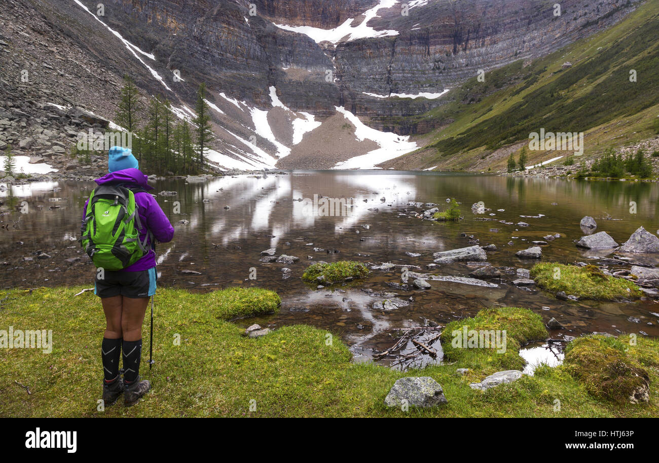 Randonnée femelle isolée regardant la vue sur l'eau du lac Calm Mountain, paysage panoramique des montagnes Rocheuses canadiennes, parc national Banff Banque D'Images