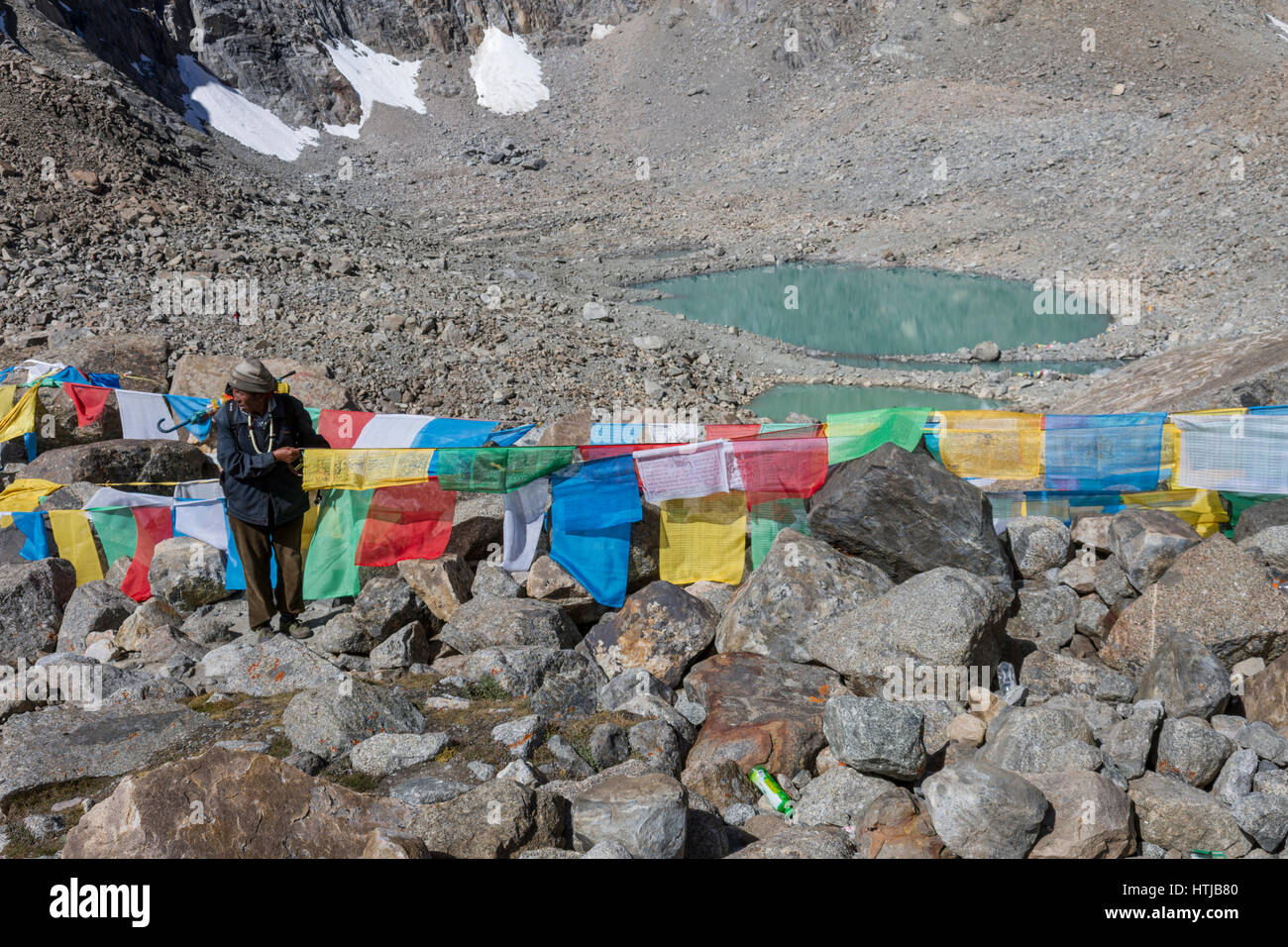 L'homme bouddhiste tibétain, nouer le pèlerin Lung ta les drapeaux de prières à Dolma La pass en route Mt. Kailash Kora Banque D'Images