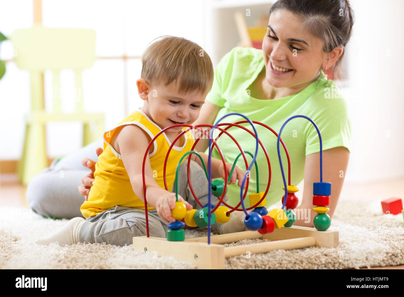 Kid garçon joue avec jouet éducatif à la maternelle à la maison. Heureux mère regardant son fils intelligent. Banque D'Images