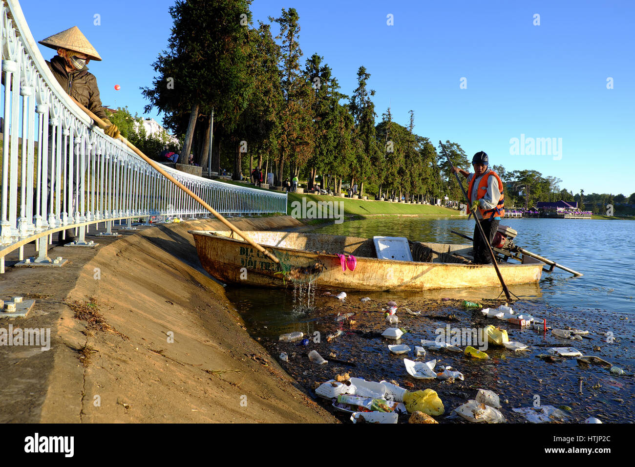 DA LAT, VIET NAM, Vietnamien travailleur d'assainissement travaille sur bateau pour pêcher les ordures hors de l'eau, déchets sur l'eau faire la pollution, scène de lac de Xuan Huong Banque D'Images