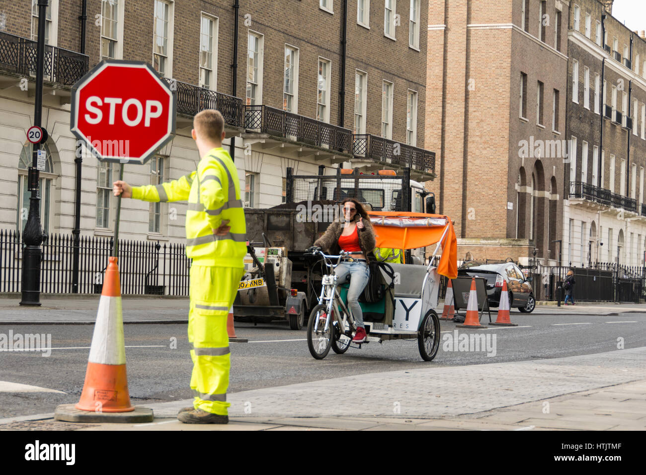 Un ouvrier en vêtements de haute visibilité avec un panneau d'arrêt sur une rue calme de Londres à Bloomsbury, Angleterre, Royaume-Uni Banque D'Images