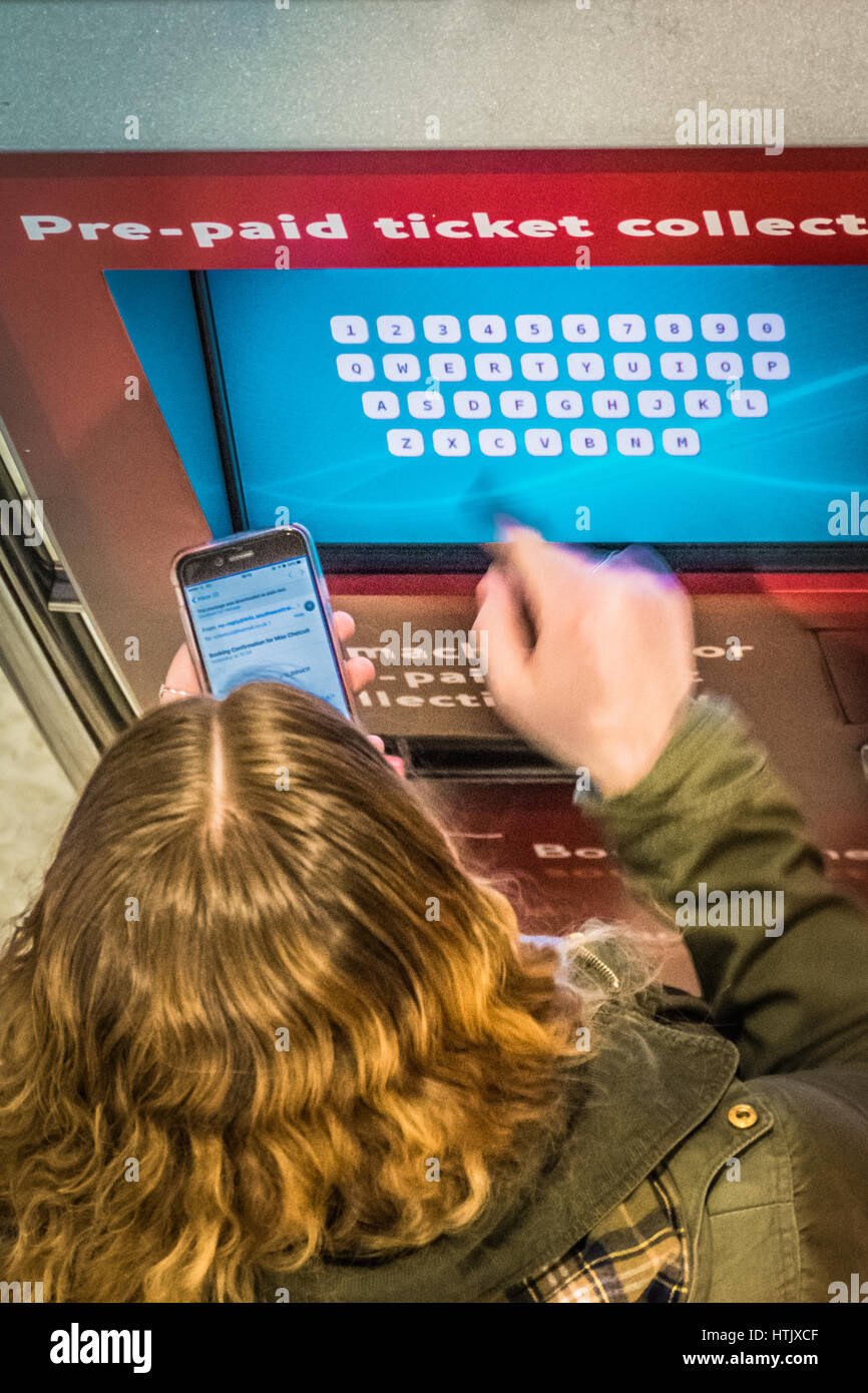 La collecte d'un passager un billet à une machine en libre-service à Londres, Royaume-Uni Banque D'Images