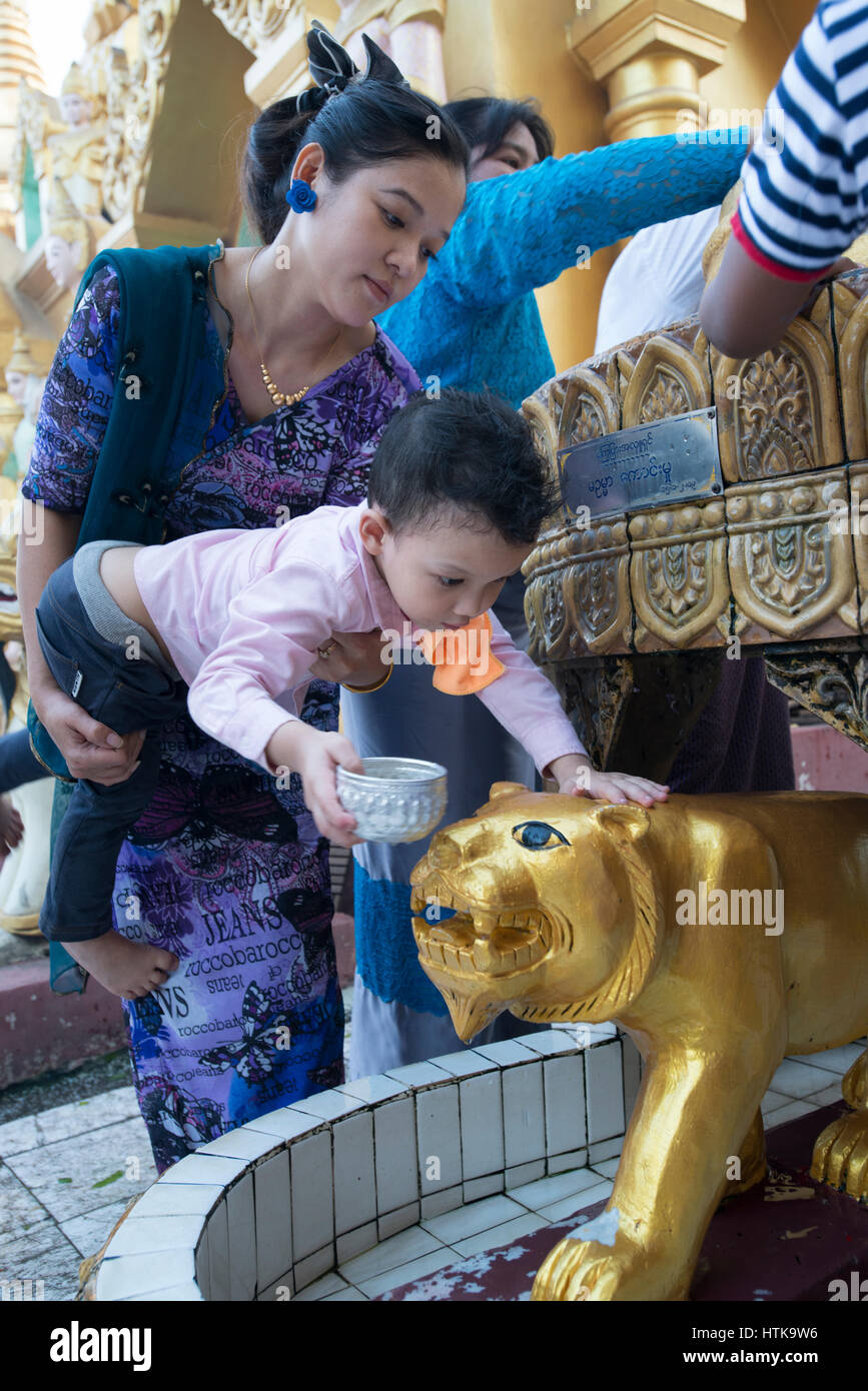 La pagode Shwedagon, Yangon, Myanmar, le 12 mars 2017. Une mère tient son enfant comme il lave une divinité animale associée à son jour de naissance au cours de la pleine lune festival. tabuang la pleine lune est une période importante pour les pèlerins de se rendre au Myanmar pagode bouddhiste le plus sacré. tabuang la pleine lune est le plus propice et se produit chaque année au mois de mars. crédit : Trevor Thompson/Alamy live news Banque D'Images