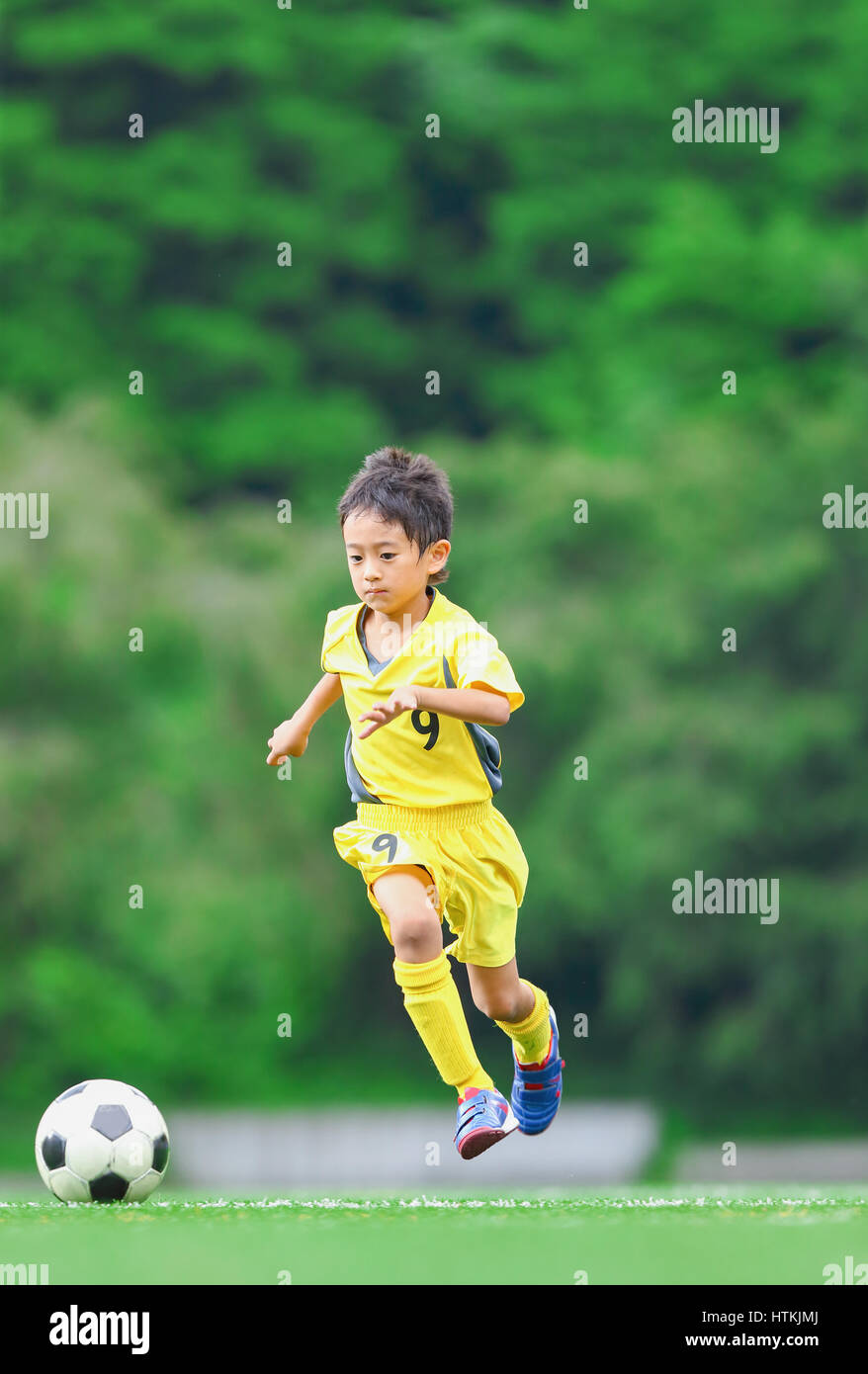 Enfant jouant au football japonais Banque D'Images