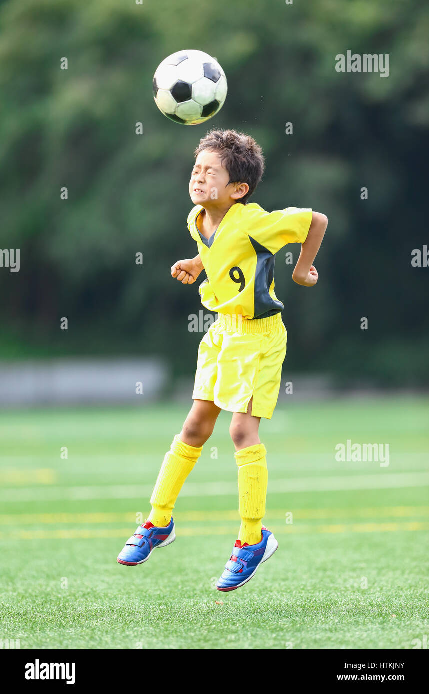 Enfant jouant au football japonais Banque D'Images