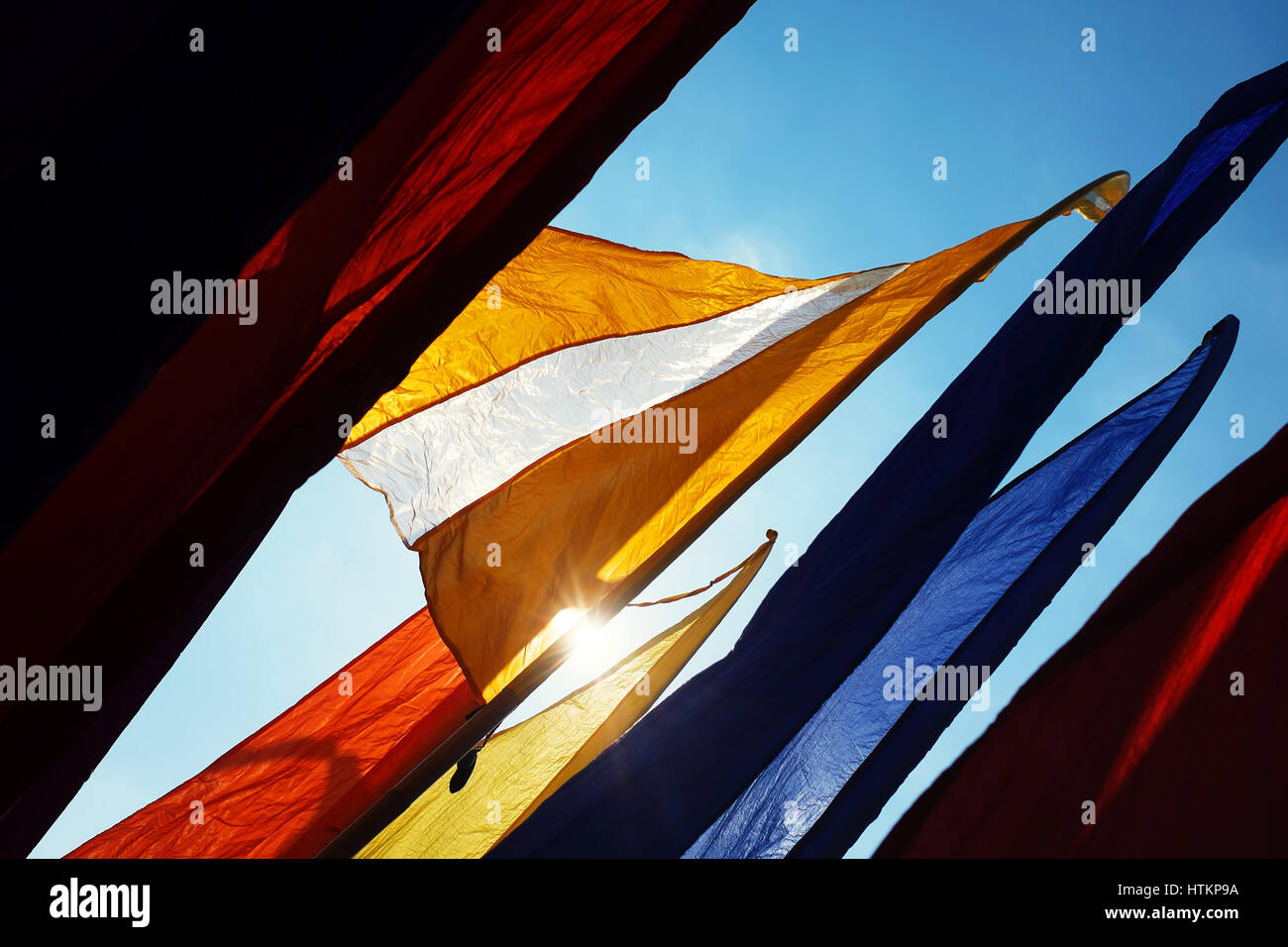 Drapeaux bannière aux couleurs vives clapote contre ciel ensoleillé bleu Banque D'Images