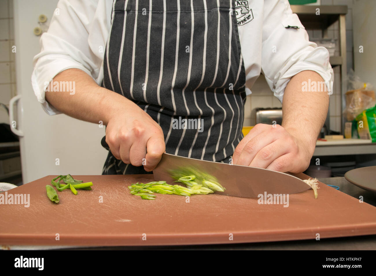 Chef chopping oignons de printemps avec un grand couteau Banque D'Images
