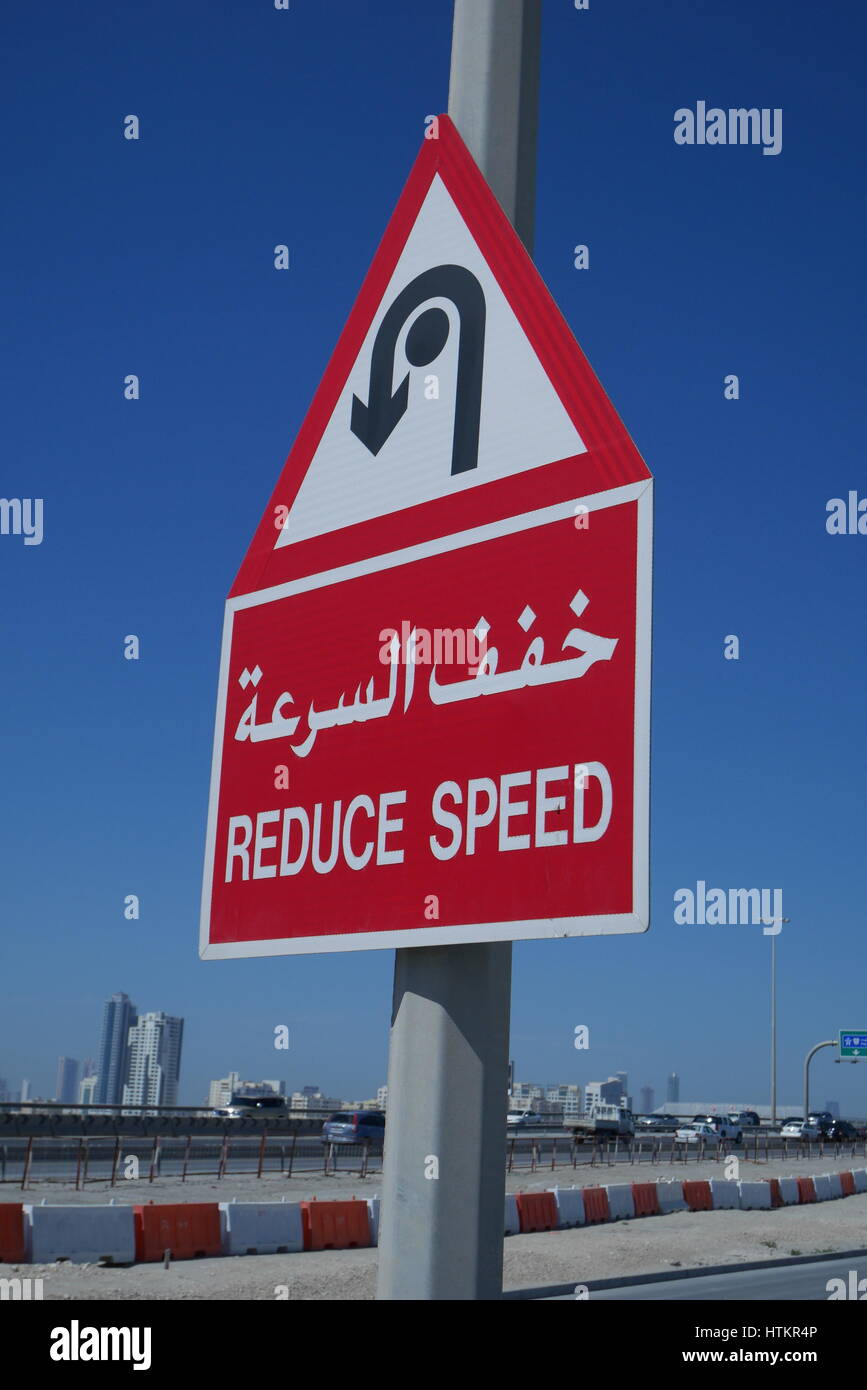 Inscription en arabe et français avertissement les conducteurs à réduire leur vitesse parce qu'il y a un rond-point devant, Sitra Causeway, Bahreïn Banque D'Images