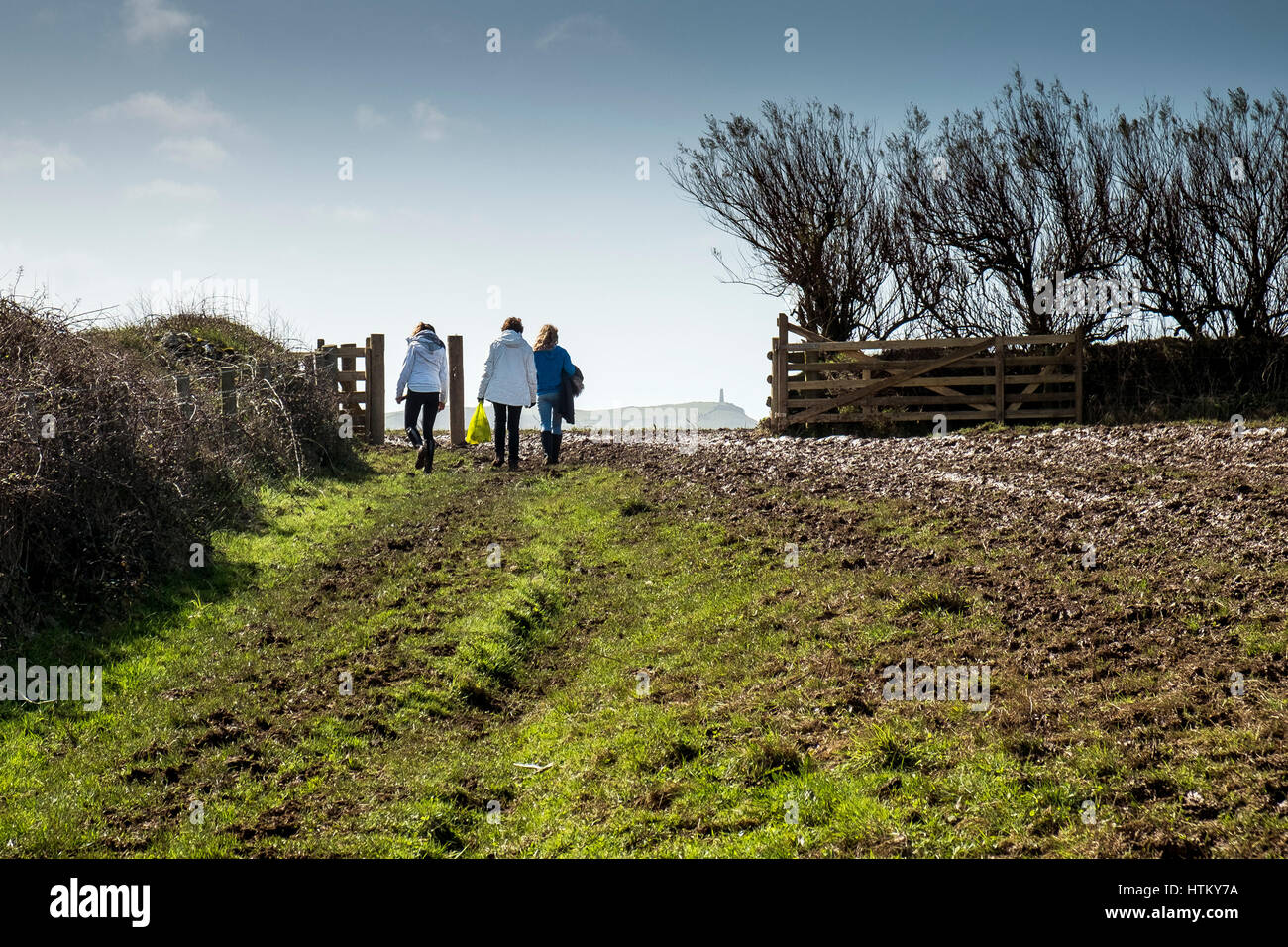 Trois personnes marchant gate Pentire champ pointe Cornwall Banque D'Images