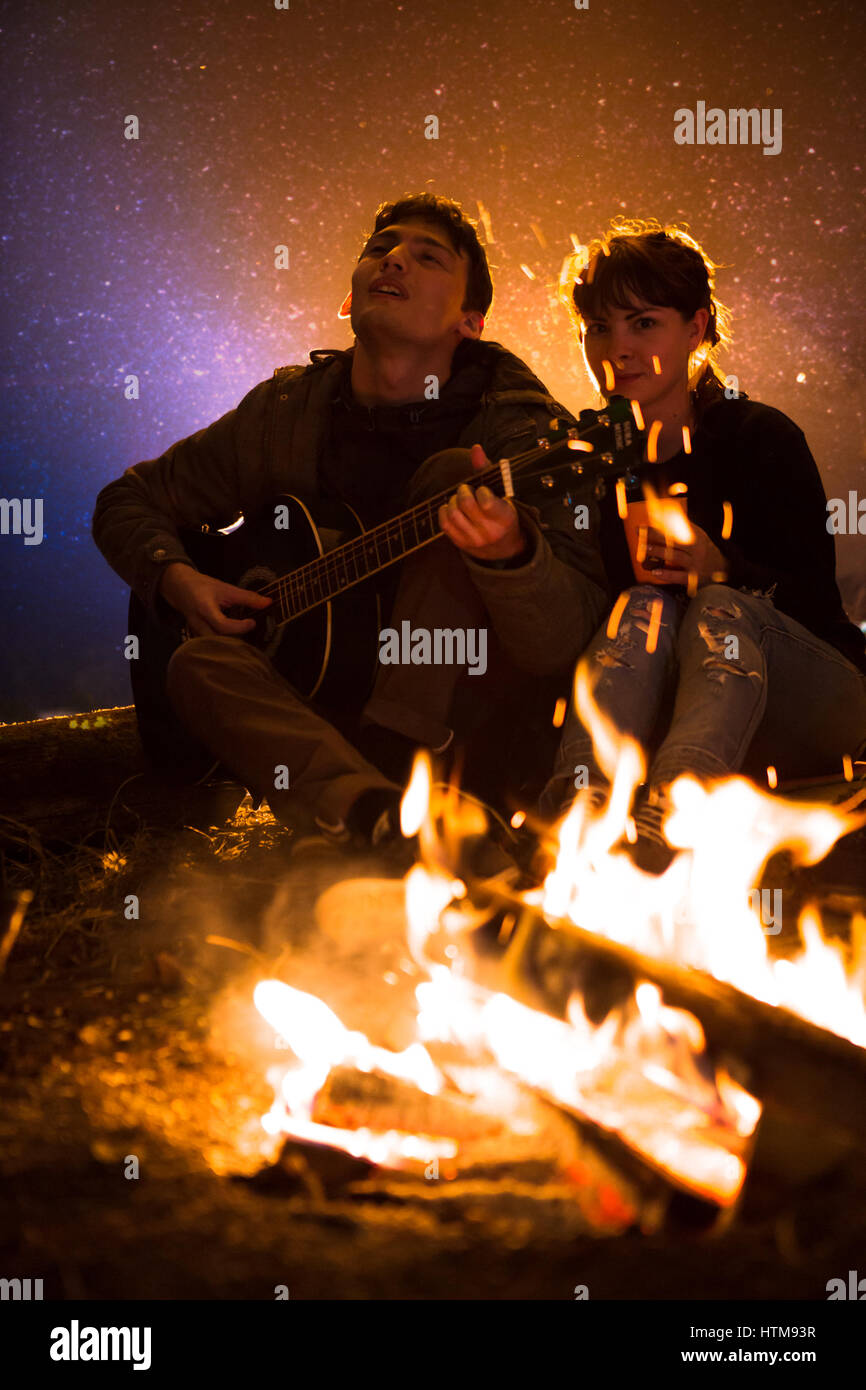 L'homme joue de la guitare et de la femme sur l'incendie sur le fond du  ciel étoilé Photo Stock - Alamy