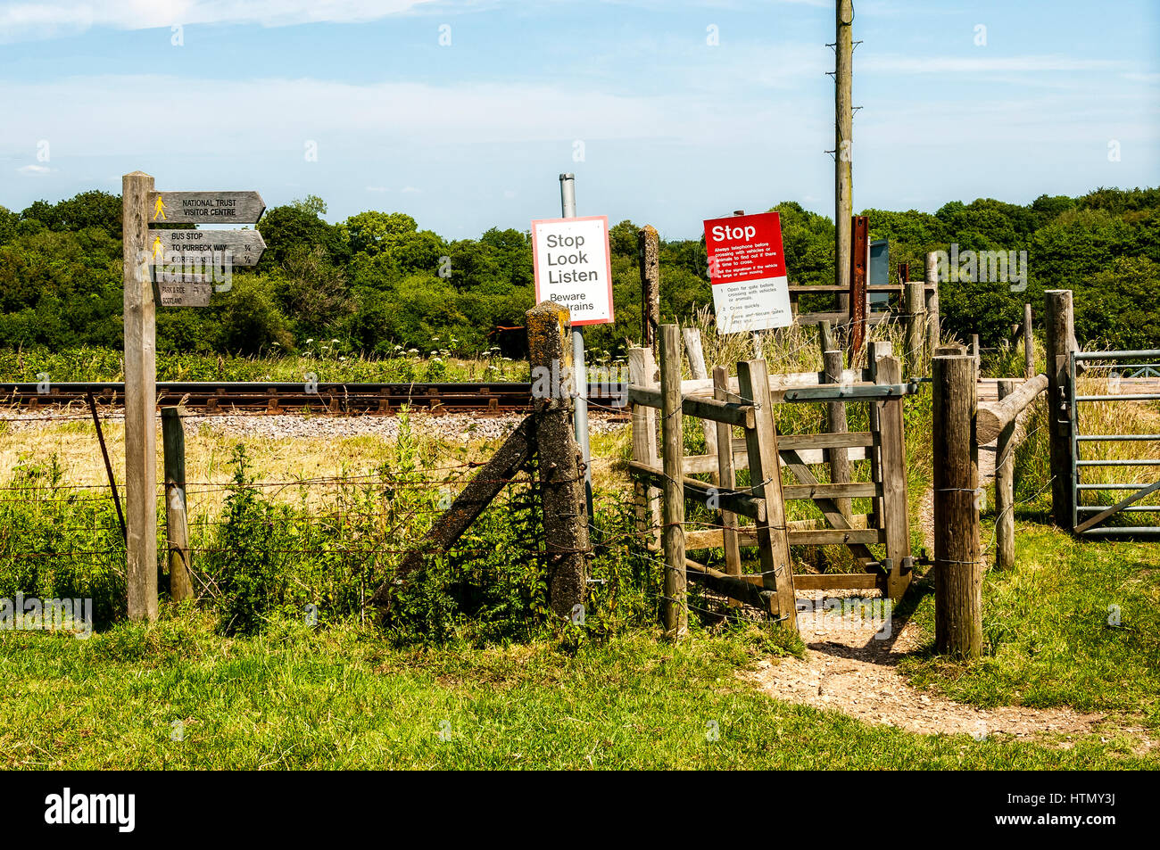 Un passage pour piétons à travers bois gated lignes de chemin de fer entièrement complétées par des panneaux de direction et d'avertissement dans la campagne anglaise sunkissed chaud Banque D'Images