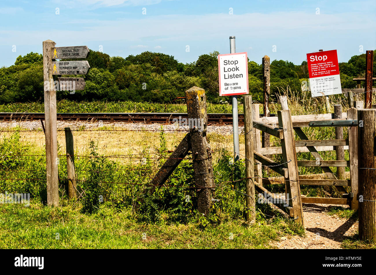 Un passage pour piétons à travers bois gated lignes de chemin de fer entièrement complétées par des panneaux de direction et d'avertissement dans la campagne anglaise sunkissed chaud Banque D'Images