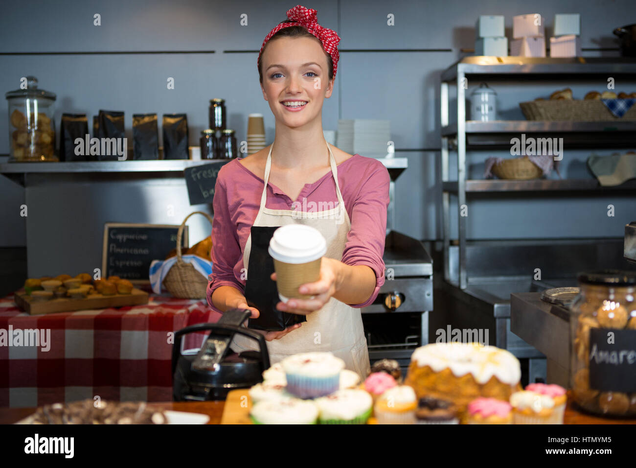 Portrait de femme tenant un sac de café et Coffee cup at counter in market Banque D'Images