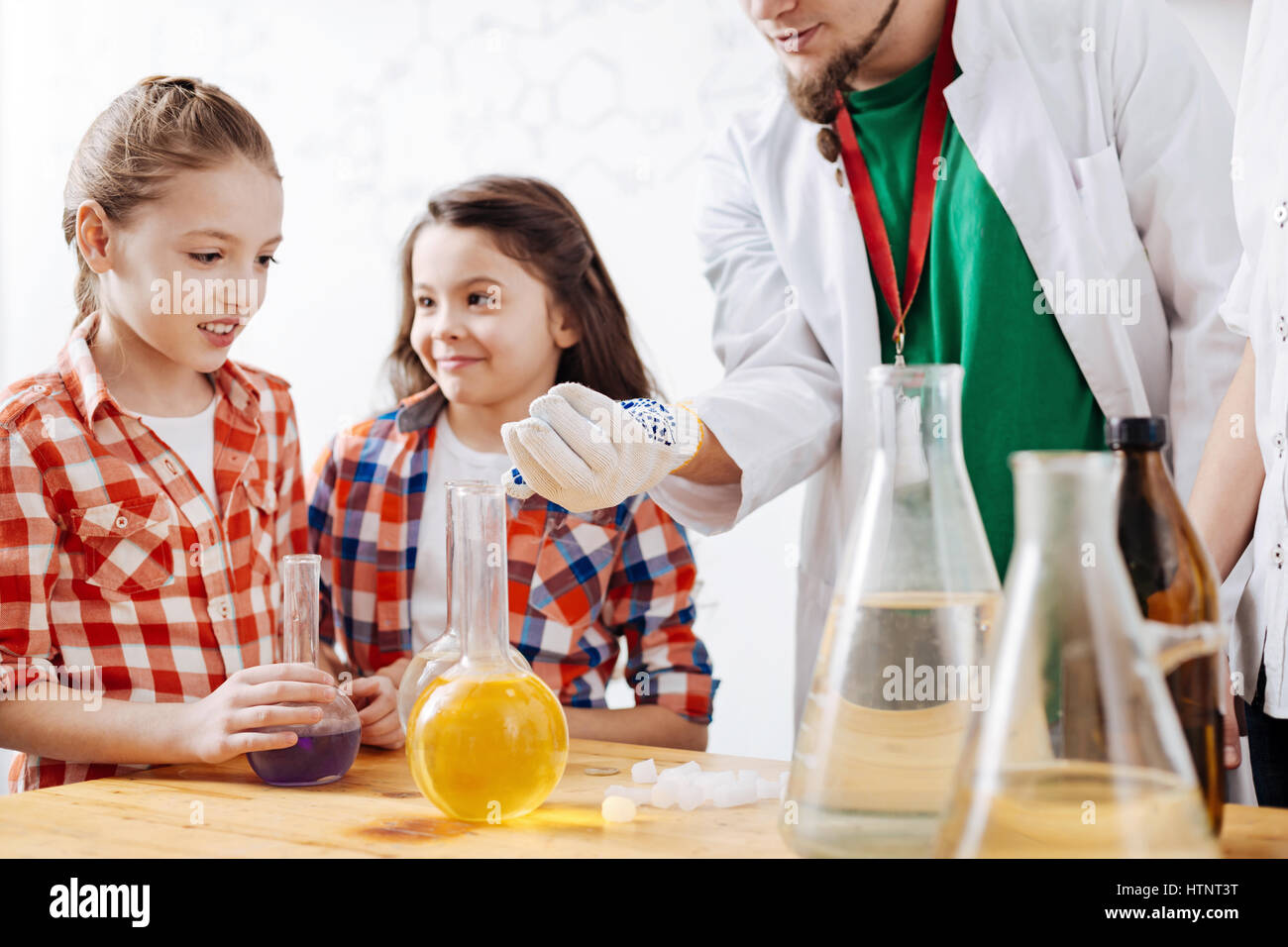 Obtenir intéressés. Joli mignon fille curieuse, debout près de la table et à la recherche à la main pendant que les scientifiques s'intéressant à la science Banque D'Images