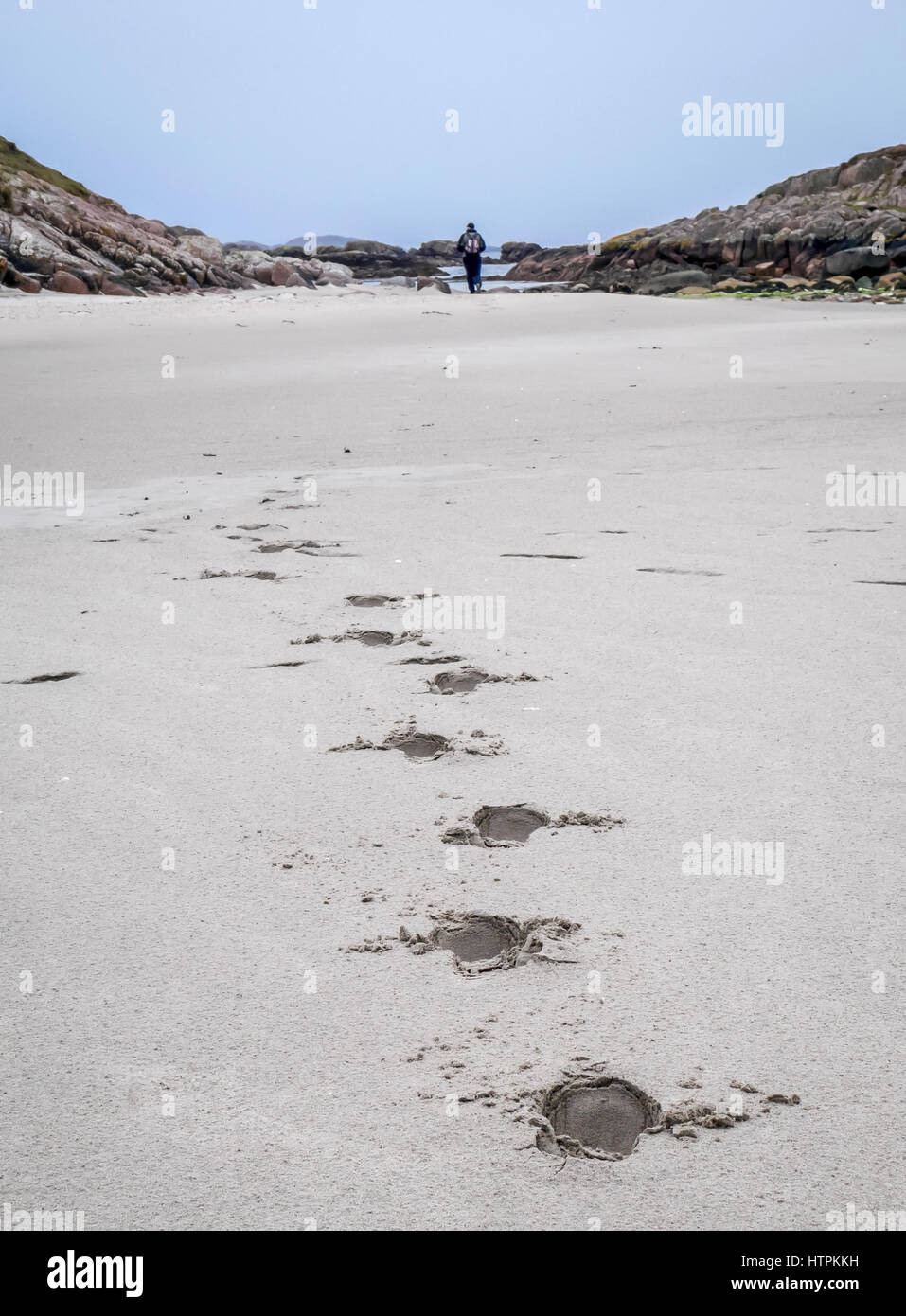 Des empreintes de pas dans le sable blanc qui mène à distance avec l'homme solitaire marche loin, Isle of Mull, Scotland, UK Banque D'Images