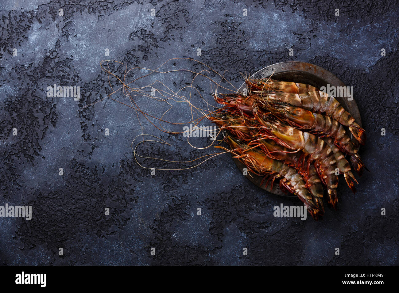 La crevette tigrée frais crus en plaque métallique sur fond noir copy space Banque D'Images