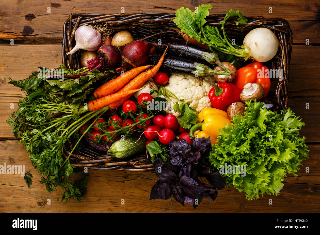 Des légumes frais dans le panier sur fond de bois Banque D'Images