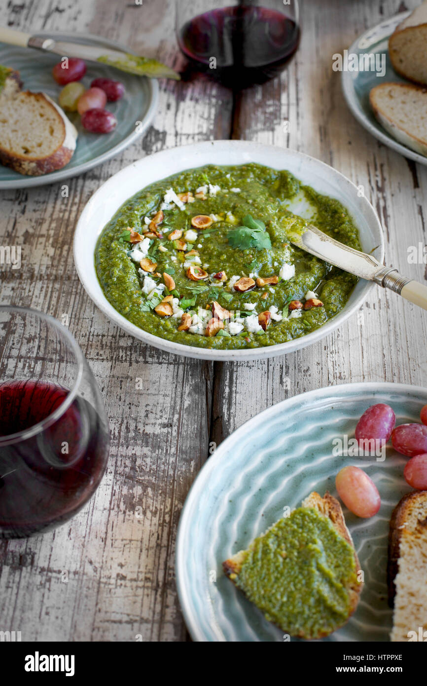 Pesto de coriandre Noisette Gorgonzola servi dans un bol en céramique avec crostini, les raisins et le vin. Photographié en vue de dessus sur un bois rustique/white background Banque D'Images