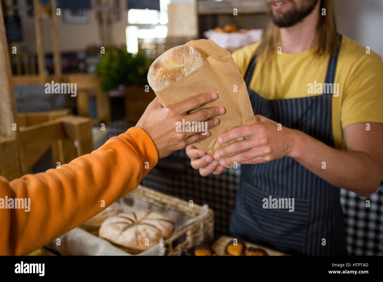 Le client reçoit des hommes un colis du personnel au comptoir d'une boulangerie Banque D'Images