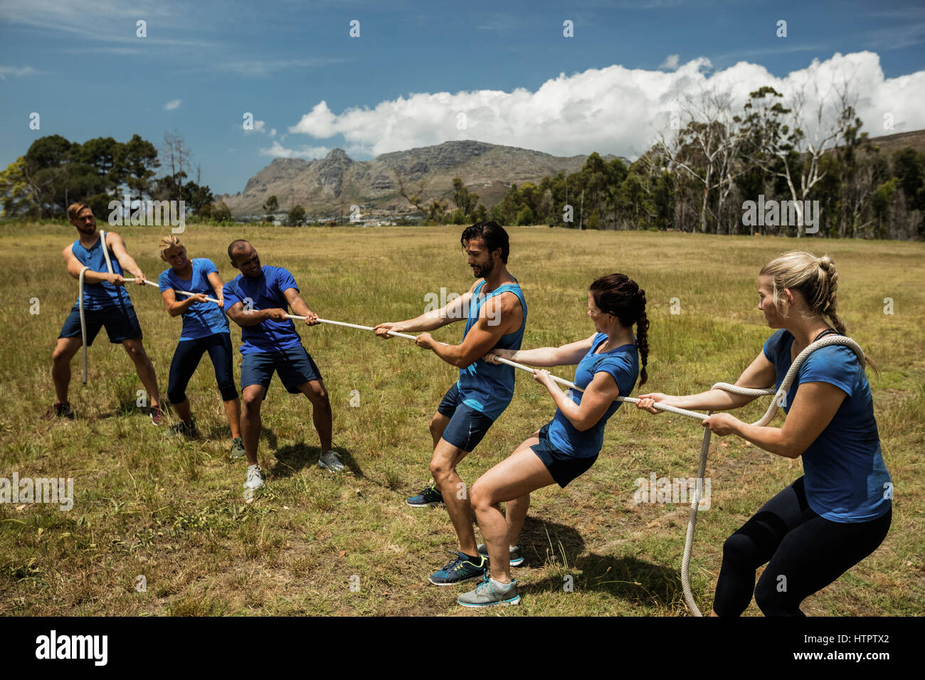Gens jouer remorqueur de la guerre au cours d'obstacle dans boot camp Cours de formation Banque D'Images
