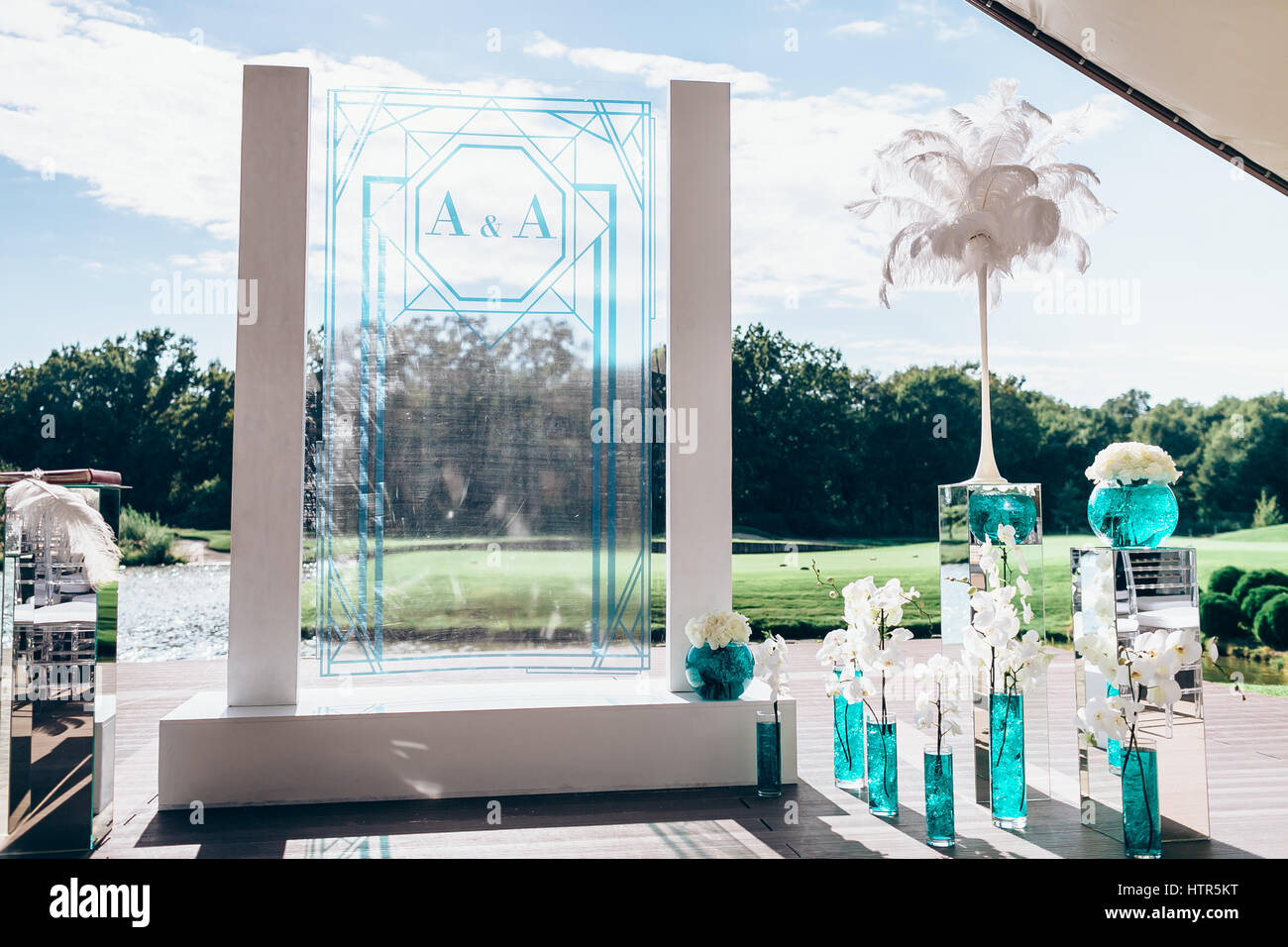 Arche de mariage blanc avec des bouquets de fleurs, orchidées et peon en vases de verre avec un liquide bleu et blanc big plume Banque D'Images