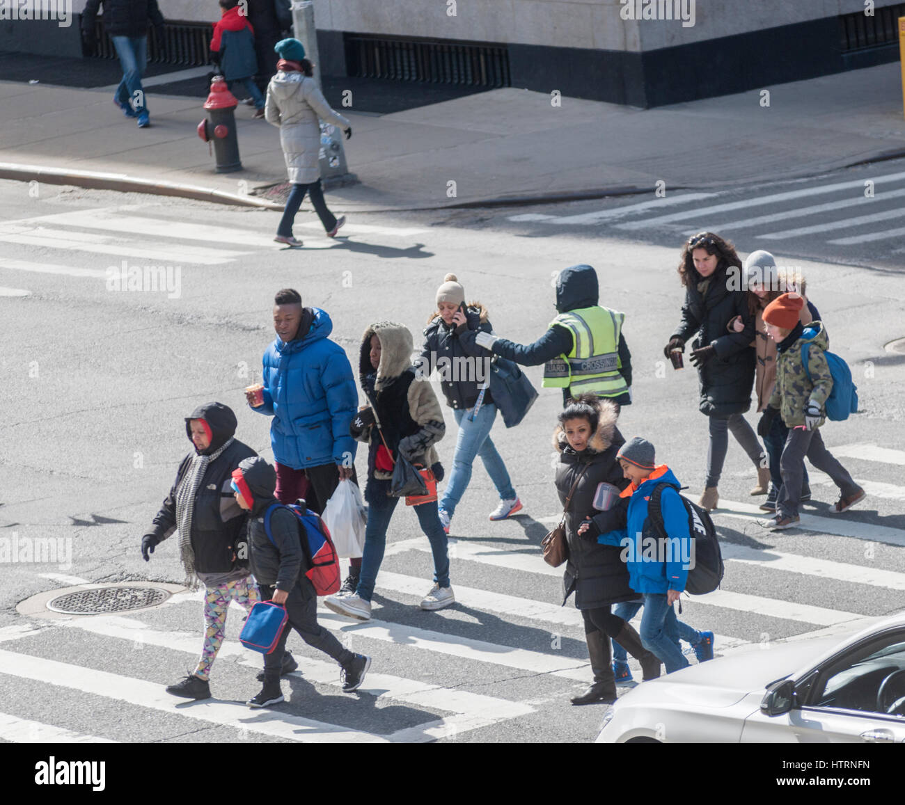 Les étudiants et leurs tuteurs sous l'œil attentif d'un cross crossing guard 9e Avenue en face de PS 33 à Chelsea à New York Lundi, Mars 13, 2017. En raison de la tempête approchant le maire Bill De Blasio a commandé les écoles pour être fermé le mardi, ainsi qu'un côté de la rue, parking étant suspendu. (© Richard B. Levine) Banque D'Images