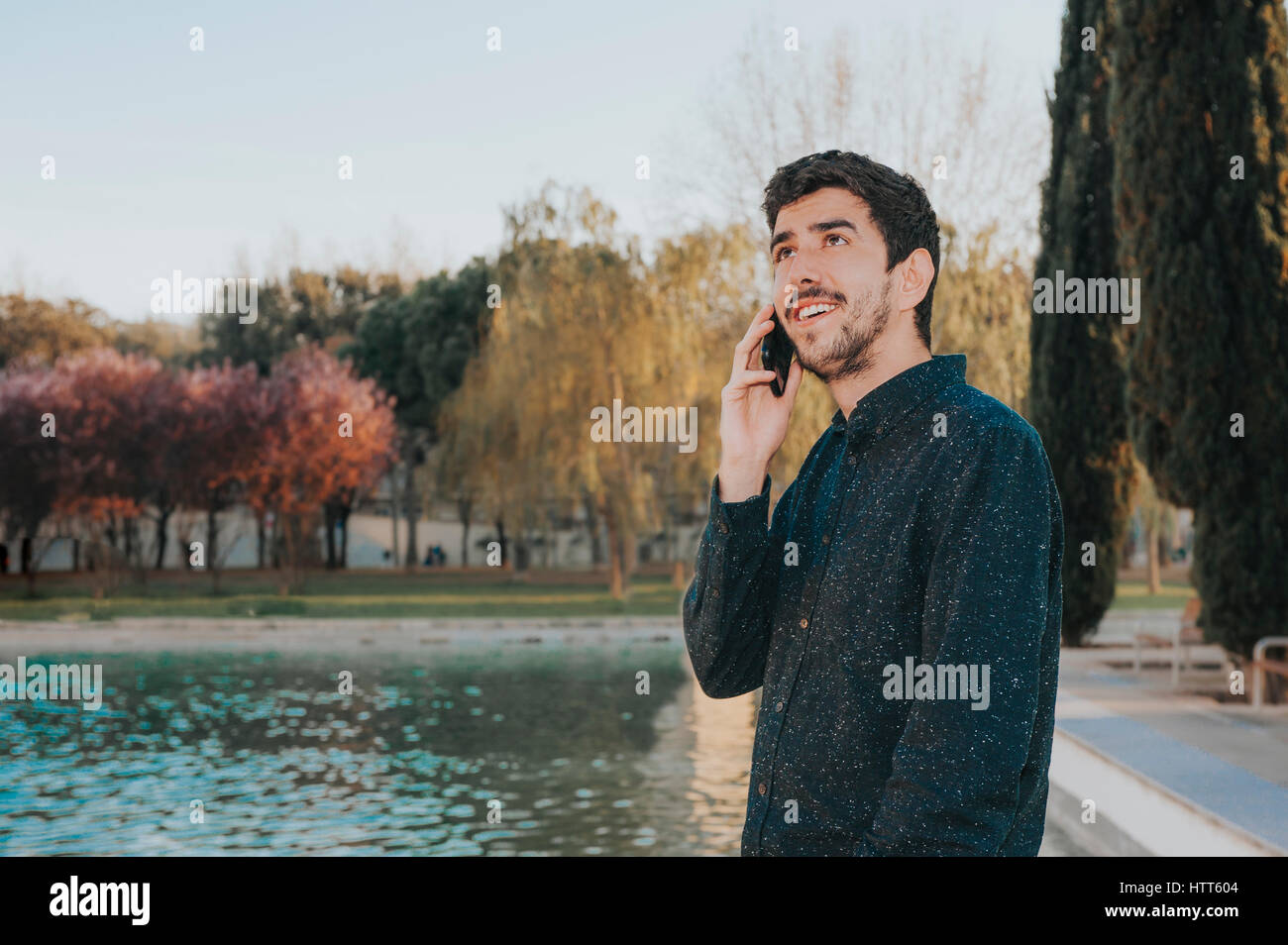 Jeune homme mexicain parler au téléphone dans un parc Banque D'Images