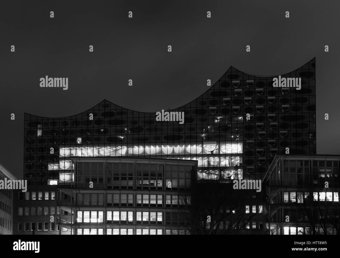 Hambourg, Allemagne - 9 mars 2017 : l'elbe Philharmonic Hall dans la zone du port Hafencity derrière plusieurs édifices dans la nuit en noir et blanc. Banque D'Images