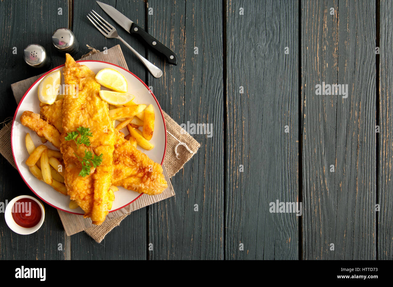 Deux morceaux de poisson enrobés de pâte sur une plaque avec des jetons sur une table de bois avec de l'espace Banque D'Images