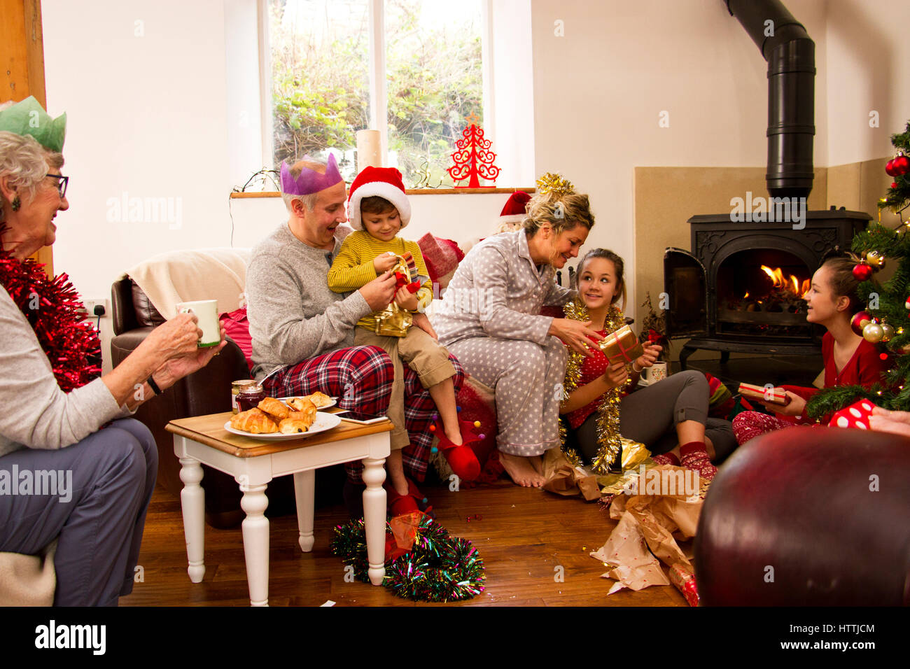 Family enjoying matin de Noël ensemble. Les enfants sont l'ouverture présente avec leurs parents et la grand-mère est à regarder. Banque D'Images