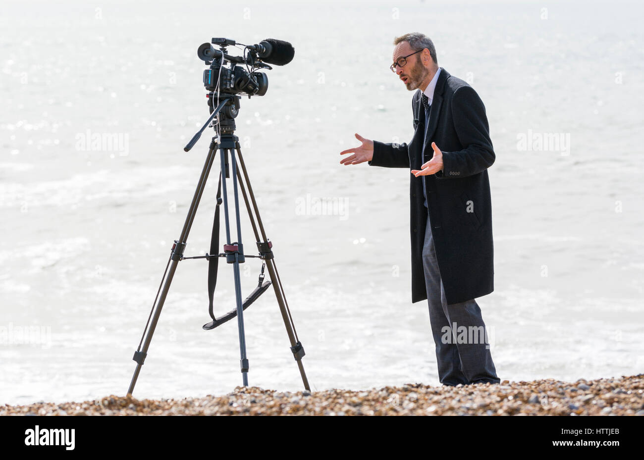 Reporter sur une plage de faire une diffusion à l'extérieur pour un téléviseur.news programme. Banque D'Images