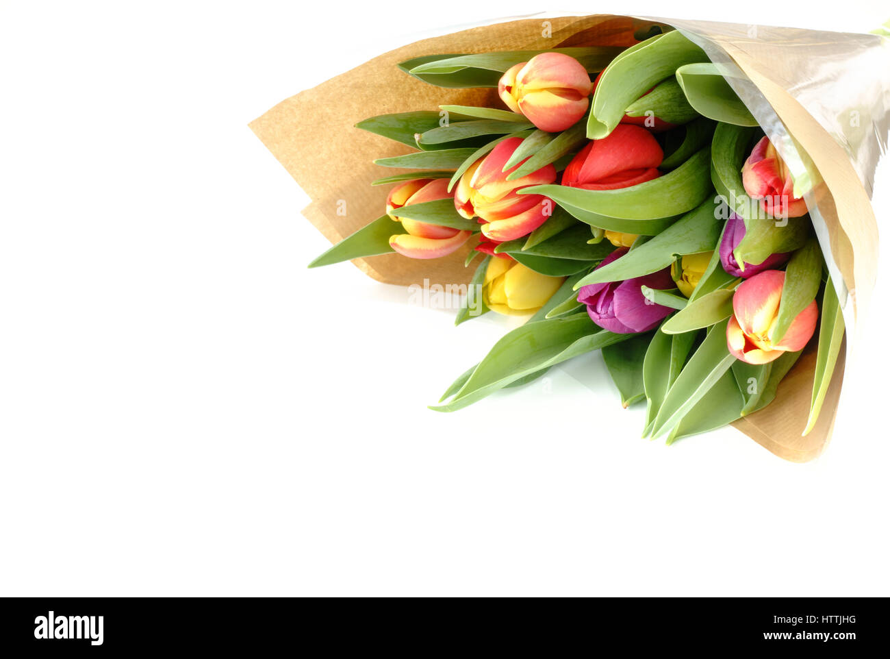 Bouquet de belles tulipes Arc-en-ciel multicolores enveloppé dans du papier brun sur fond blanc avec plein de copier l'espace. Banque D'Images