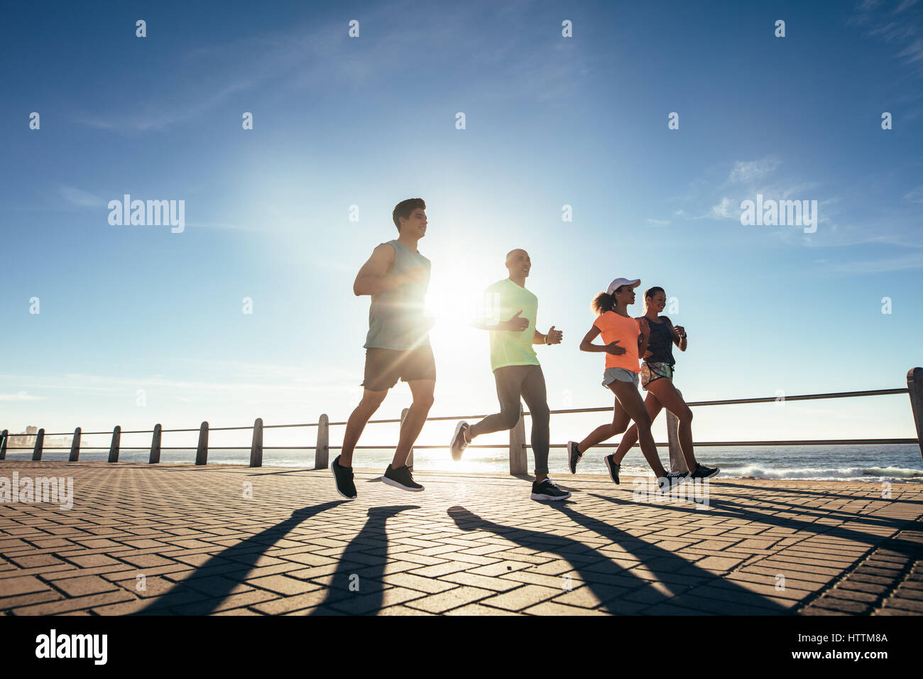 Les jeunes en marche le long d'une promenade en bord de mer. La formation à l'extérieur par les coureurs de mer sur une journée ensoleillée. Banque D'Images