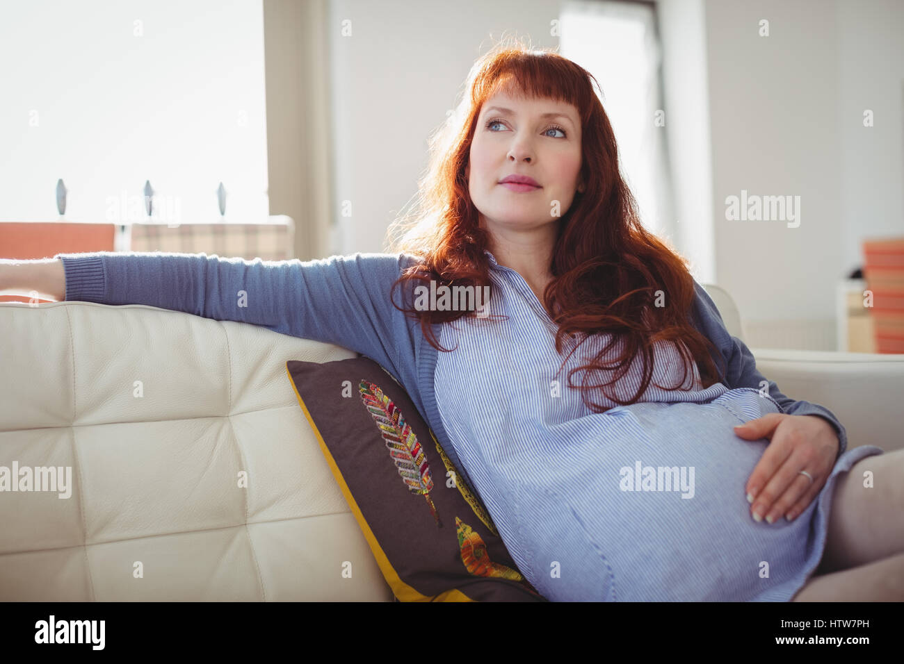 Une femme enceinte relaxing in living room Banque D'Images