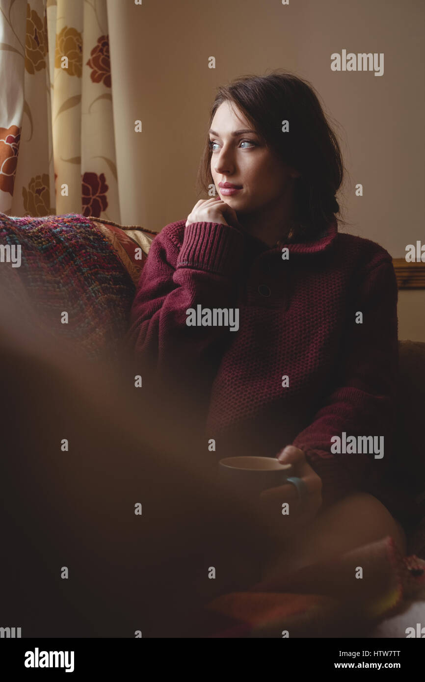 Une femme assise et tenant une tasse de café Banque D'Images