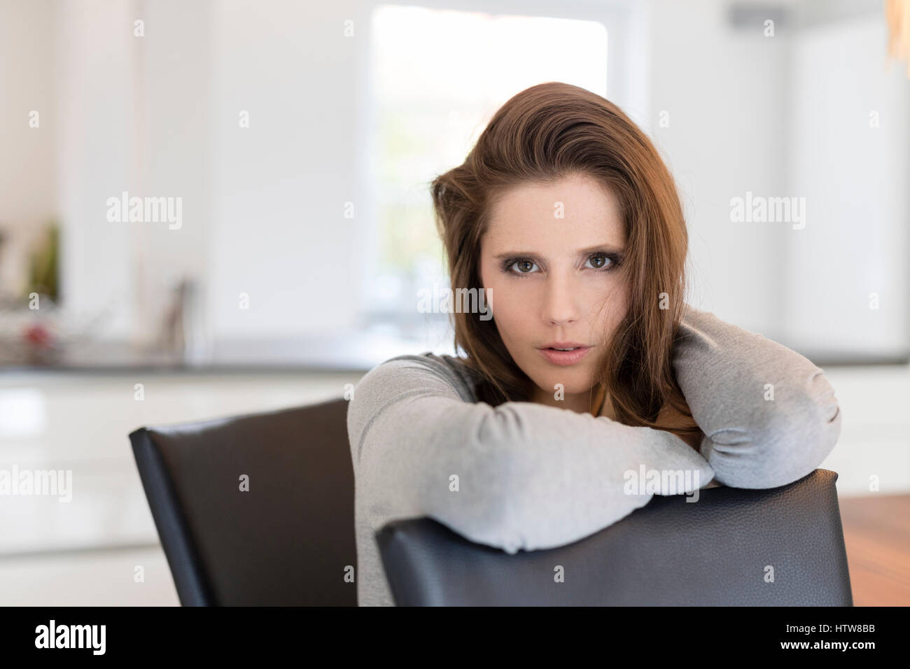 Young woman sitting at table in dining room Banque D'Images