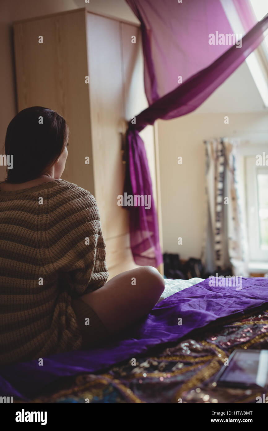 Femme assise sur le lit dans la chambre Banque D'Images