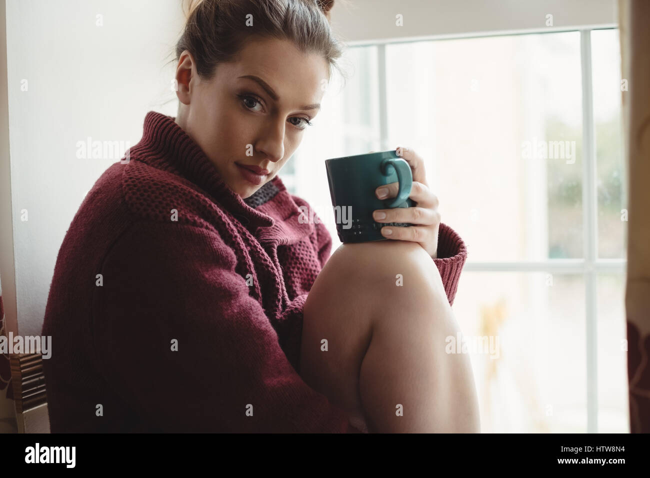 Portrait de femme assise au rebord de fenêtre et holding Coffee cup Banque D'Images