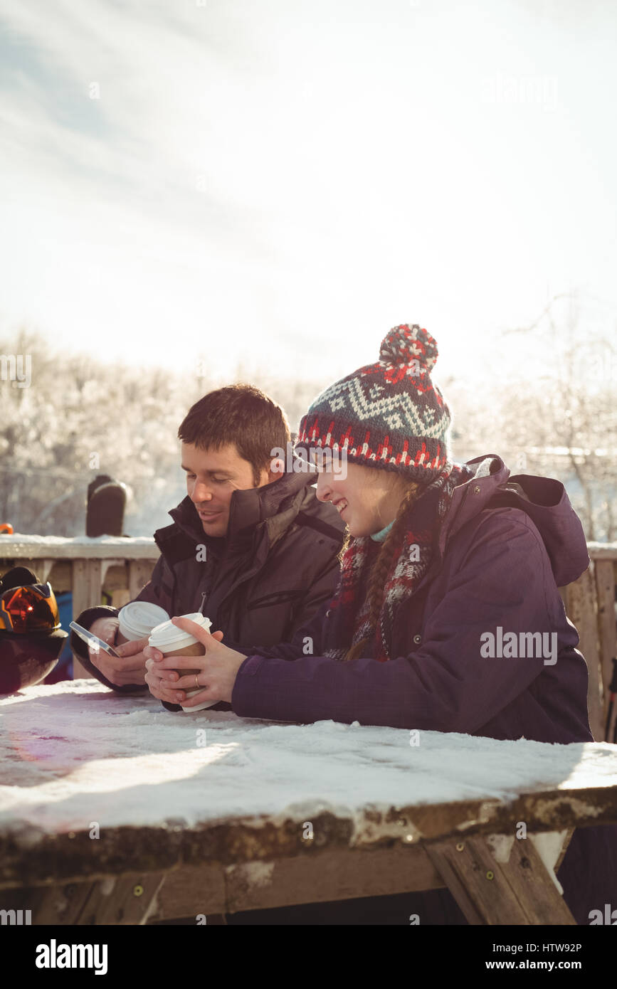 Skieur heureux couple using mobile phone and laptop at table Banque D'Images