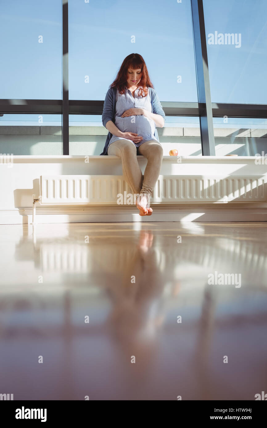 Une femme enceinte assis près de fenêtre dans salle de séjour Banque D'Images