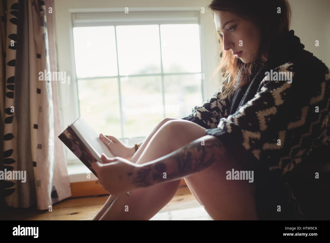 Femme assise près de la fenêtre et la lecture d'un livre Banque D'Images