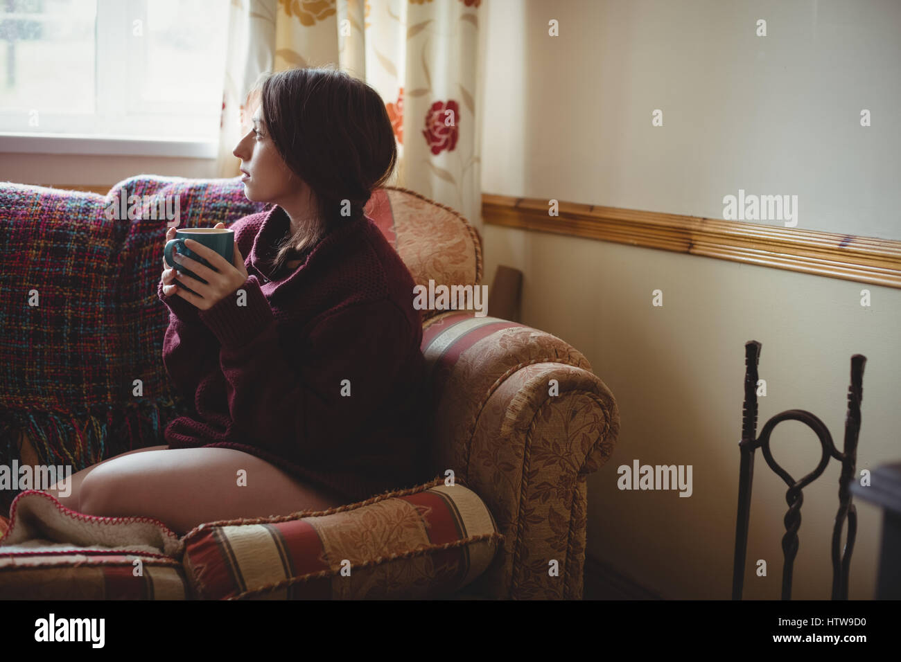 Une femme assise et tenant une tasse de café Banque D'Images